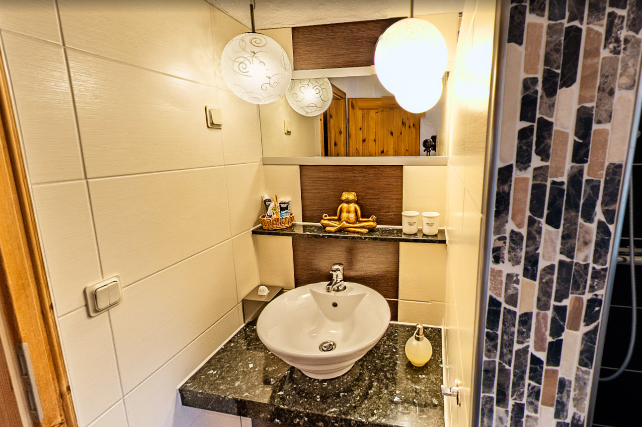 Modernes Badezimmer der Pension Kluge mit Waschbecken, Spiegel und stilvoller Beleuchtung.