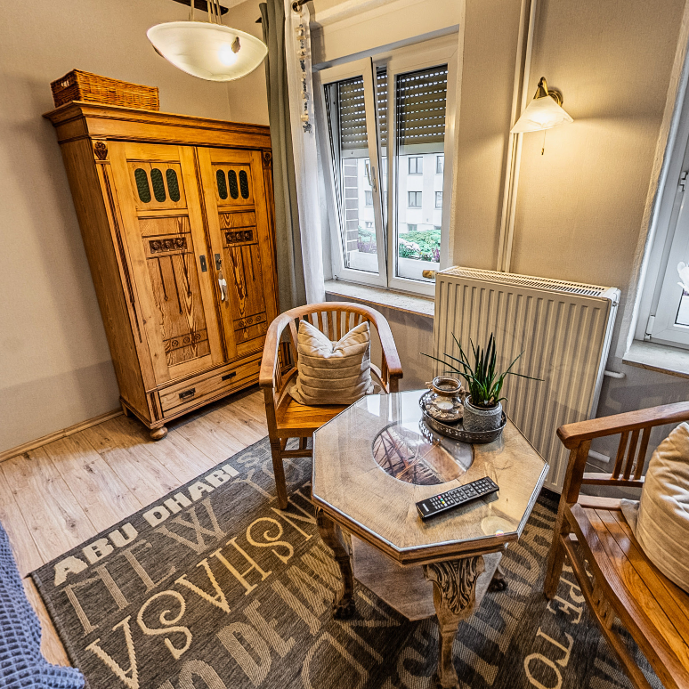 Zimmer – Pension Kluge Freiberg Zimmer der Pension Kluge in Freiberg mit Holzmöbeln, Sesseln und warmem Licht für entspannte Abende.